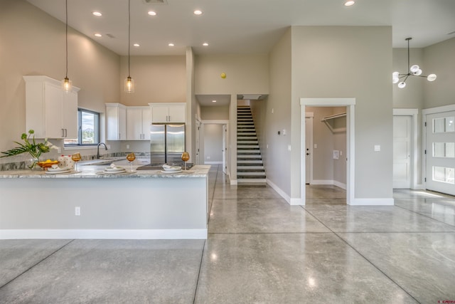 kitchen with white cabinetry, baseboards, stainless steel fridge, and a towering ceiling