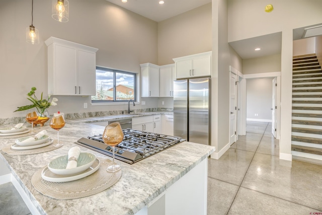 kitchen featuring freestanding refrigerator, a high ceiling, white cabinets, and stovetop