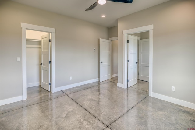 unfurnished bedroom with concrete flooring, baseboards, and a spacious closet