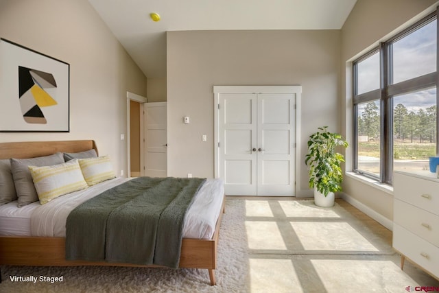 bedroom featuring baseboards, a closet, lofted ceiling, and multiple windows
