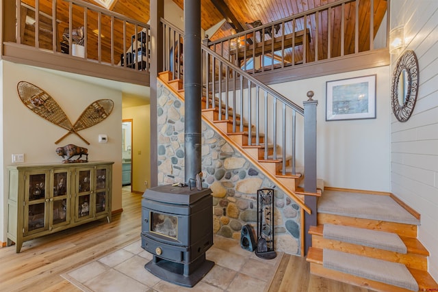 staircase with wood ceiling, a wood stove, high vaulted ceiling, and wood finished floors