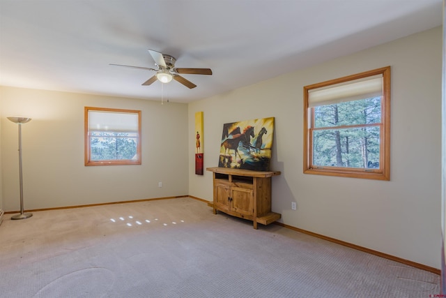 spare room featuring ceiling fan, light colored carpet, plenty of natural light, and baseboards