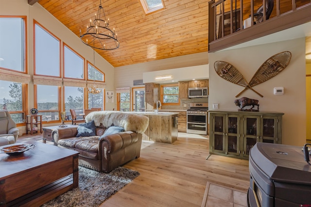 living area with a skylight, light wood-type flooring, high vaulted ceiling, wooden ceiling, and an inviting chandelier