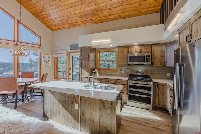 kitchen featuring stainless steel appliances, brown cabinetry, a sink, and light wood-style flooring