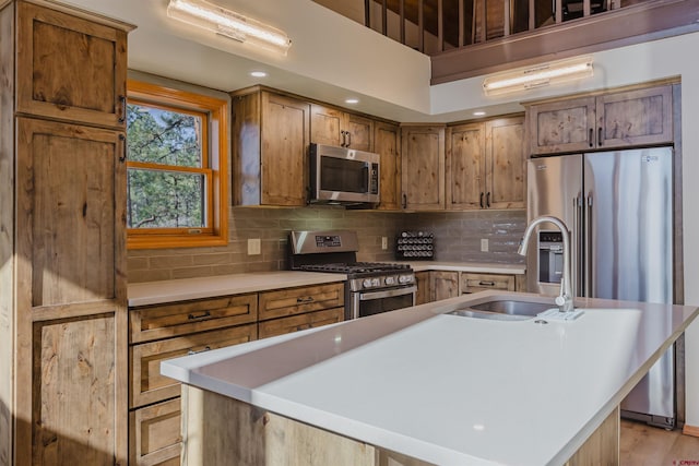 kitchen with a sink, appliances with stainless steel finishes, backsplash, and light countertops