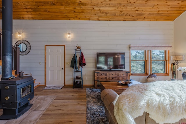 bedroom with a wood stove, wood finished floors, and wooden ceiling