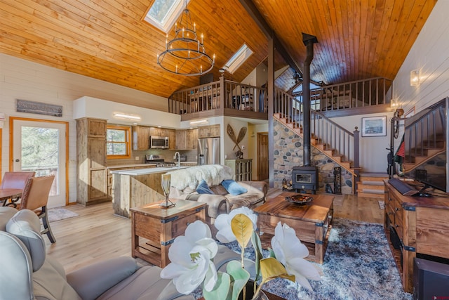 living area featuring light wood-type flooring, stairs, a notable chandelier, and wooden ceiling