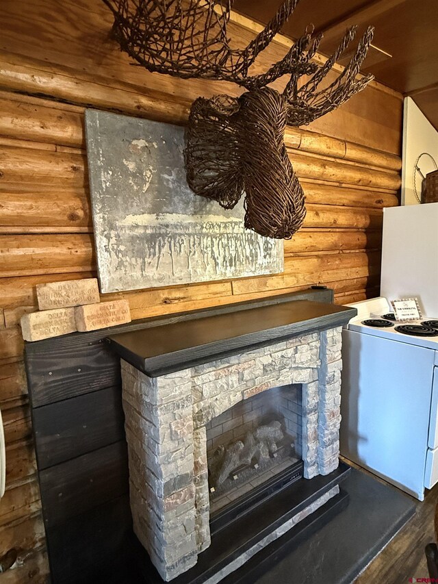 interior details with white electric range, rustic walls, wood finished floors, and a stone fireplace