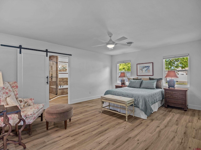 bedroom with baseboards, a ceiling fan, light wood-type flooring, and a barn door
