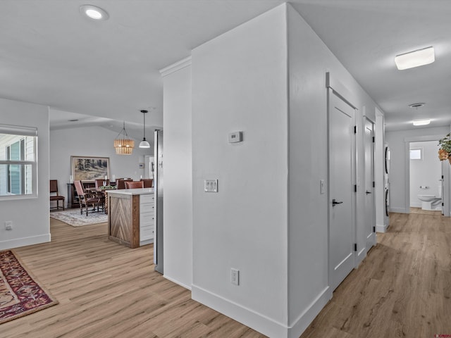 corridor featuring recessed lighting, baseboards, an inviting chandelier, and light wood-type flooring
