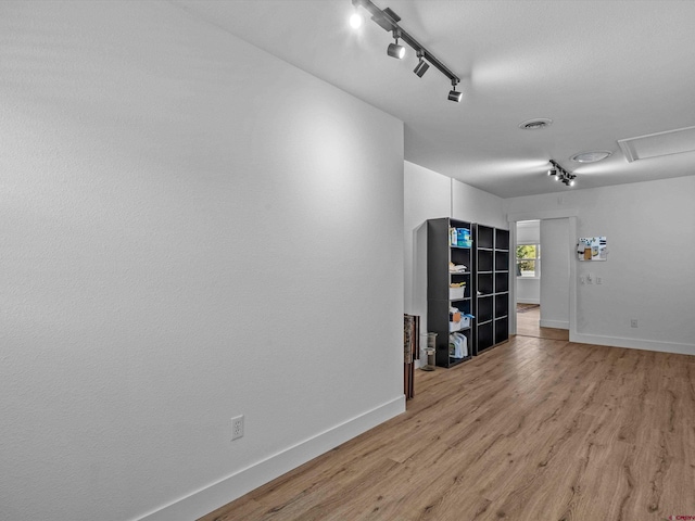 unfurnished room with baseboards, light wood finished floors, and rail lighting