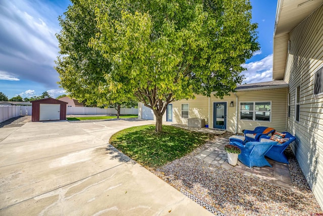 view of yard featuring fence, concrete driveway, and a garage