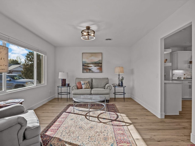 living room featuring baseboards, visible vents, and light wood-type flooring