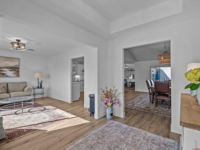 living room featuring an inviting chandelier, baseboards, and wood finished floors