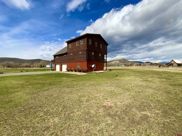409 Sierra Vista Way, Gunnison, CO 81230 - view of side of home with an attached garage, log exterior, a mountain view, a lawn, and driveway