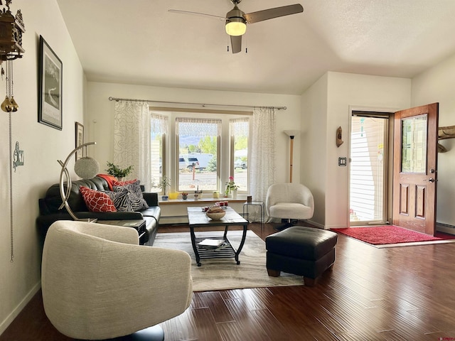 living area with a ceiling fan, baseboard heating, wood finished floors, baseboards, and a baseboard heating unit