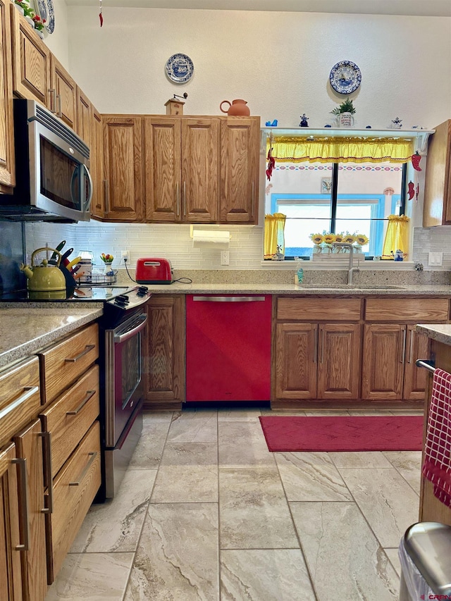 kitchen featuring backsplash, stainless steel appliances, brown cabinetry, and a sink