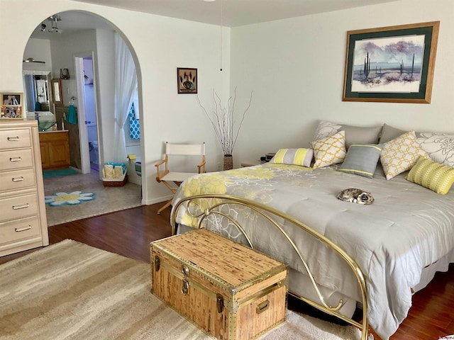 bedroom featuring arched walkways and wood finished floors