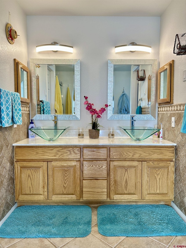 full bath featuring double vanity, a sink, tile patterned flooring, and tile walls