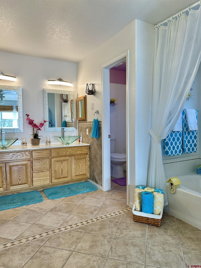 bathroom with tile patterned flooring, vanity, toilet, a textured ceiling, and a washtub
