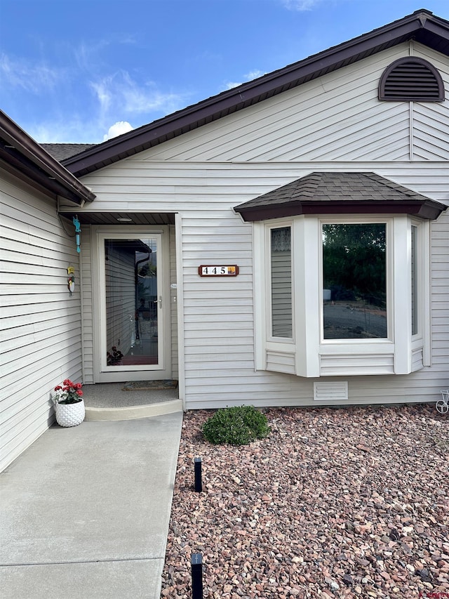 property entrance featuring a shingled roof