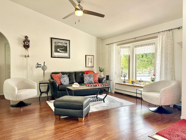 living area with a ceiling fan, arched walkways, baseboard heating, vaulted ceiling, and wood finished floors