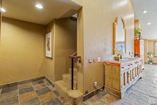 hall with baseboards, stone tile floors, stairs, and recessed lighting