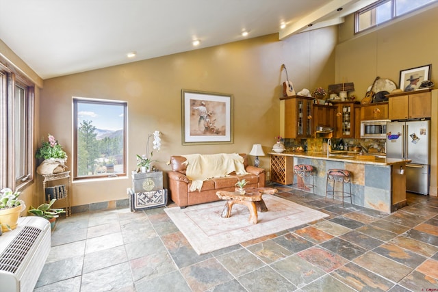 living area featuring recessed lighting, stone tile floors, and high vaulted ceiling