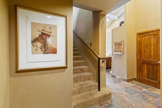 stairs with baseboards, beam ceiling, and stone tile flooring