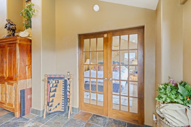 doorway to outside featuring french doors, stone finish flooring, and lofted ceiling