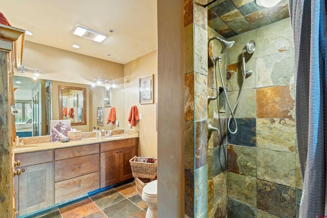 bathroom with double vanity, a sink, a walk in shower, toilet, and stone tile floors