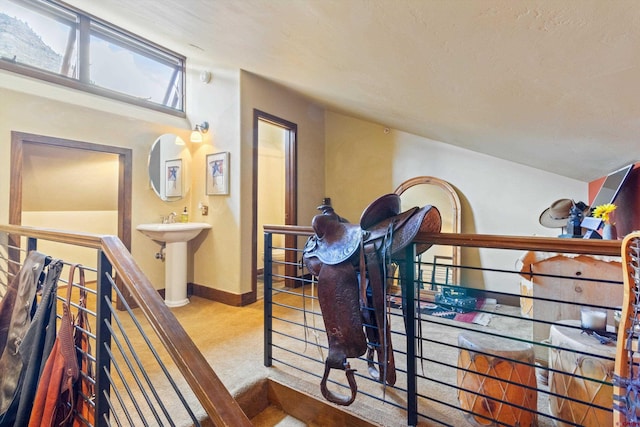 corridor with baseboards, a sink, carpet, and an upstairs landing