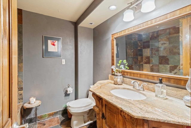 bathroom with vanity, stone finish floor, and toilet
