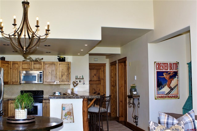 kitchen with decorative backsplash, a breakfast bar area, dark countertops, appliances with stainless steel finishes, and a chandelier