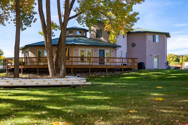 back of property featuring a yard, a deck, metal roof, and stucco siding