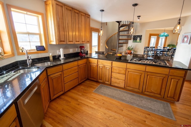 kitchen with pendant lighting, dark stone countertops, brown cabinets, light wood-style flooring, and appliances with stainless steel finishes