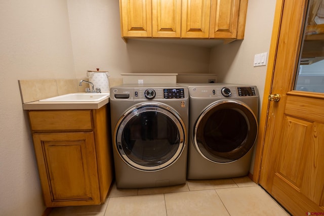 clothes washing area featuring cabinet space, light tile patterned floors, washing machine and dryer, and a sink
