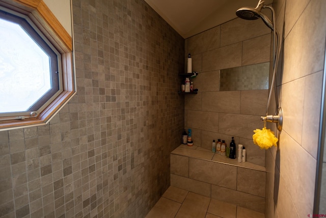 bathroom featuring lofted ceiling and tiled shower