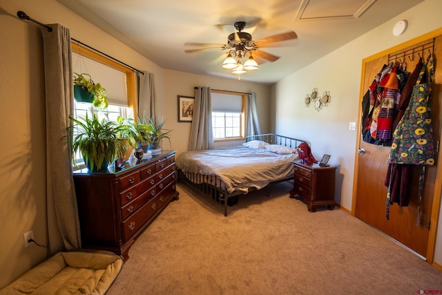 bedroom featuring a ceiling fan, light colored carpet, and attic access