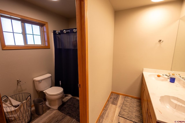 full bath with toilet, a sink, and wood finished floors