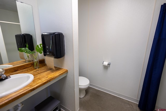 bathroom featuring toilet, baseboards, and vanity