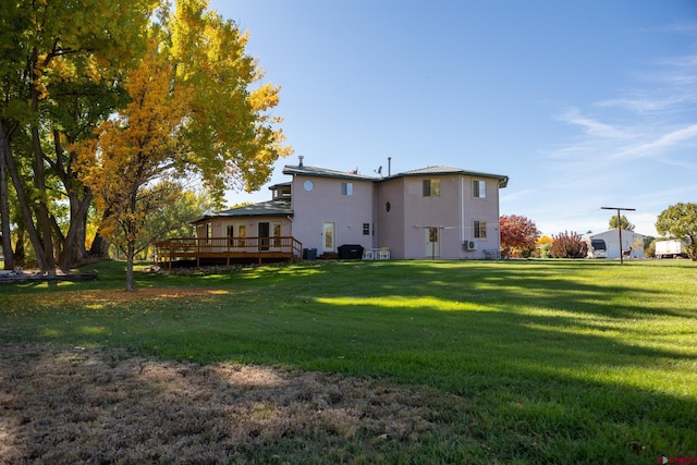 rear view of property with a lawn, a deck, central air condition unit, and stucco siding