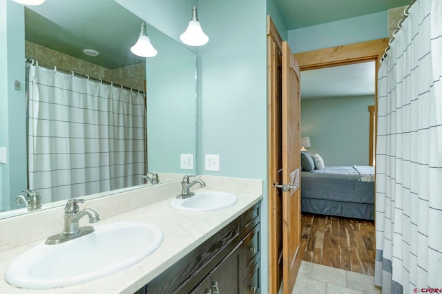 bathroom with a sink, a shower with shower curtain, double vanity, and connected bathroom