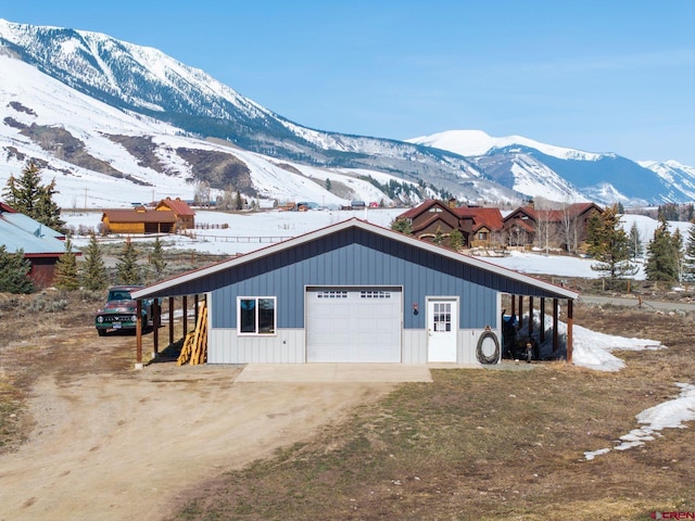 snow covered garage with a detached garage, driveway, and a mountain view