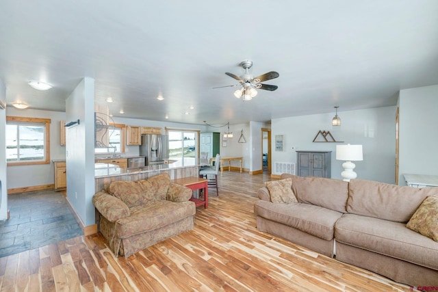 living room featuring baseboards, visible vents, ceiling fan, and light wood-type flooring