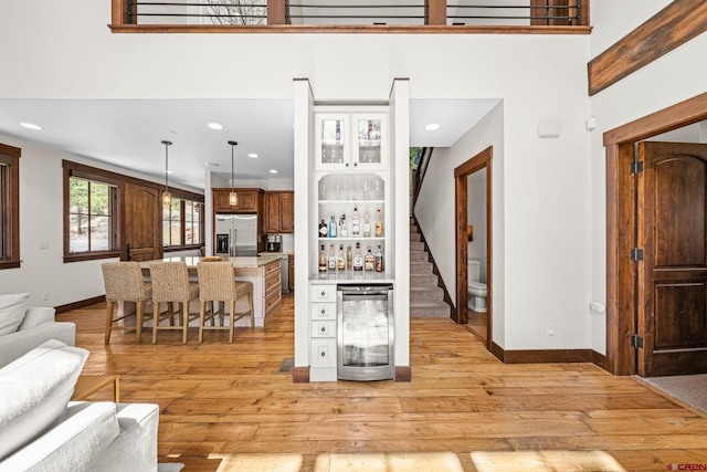 living room with light wood-style floors, baseboards, a bar, and stairs