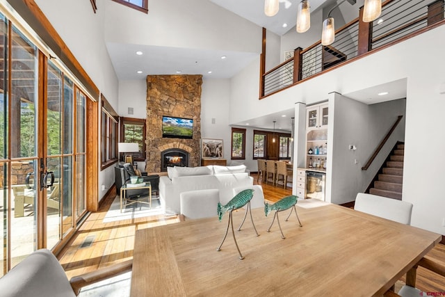 living area featuring a stone fireplace, stairs, wood finished floors, a high ceiling, and recessed lighting