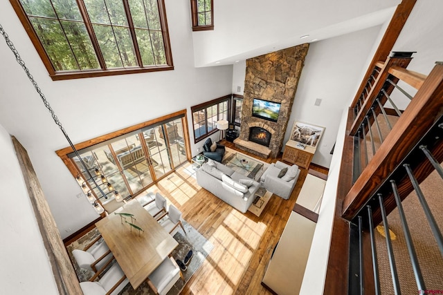 living area with wood finished floors, a high ceiling, a wealth of natural light, and a fireplace