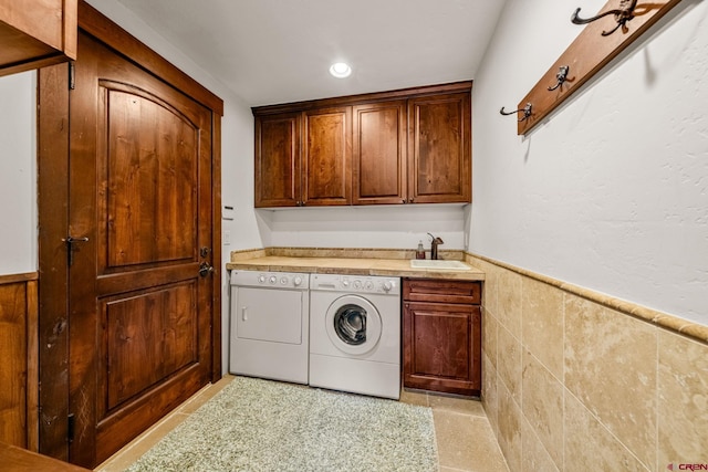 clothes washing area with cabinet space, wainscoting, a sink, recessed lighting, and washer and clothes dryer