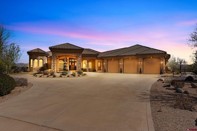 714 Washington Ct, Grand Junction, CO 81507 - mediterranean / spanish home featuring a tiled roof, curved driveway, stone siding, and an attached garage